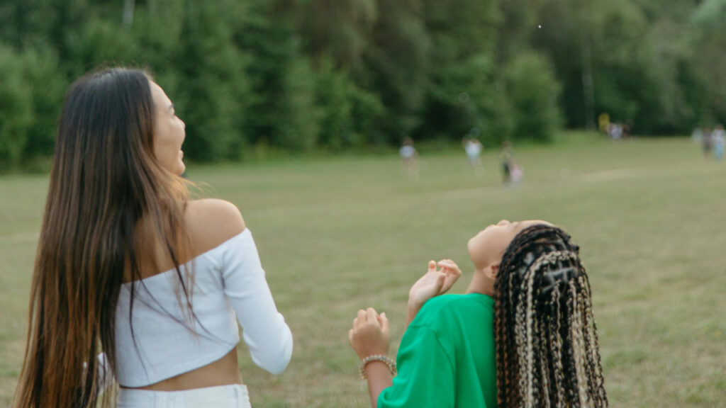 Two women laughing and enjoying a sunny day outdoors.
