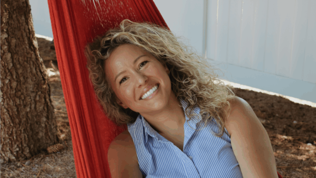 Smiling woman relaxing in a red hammock indoors.