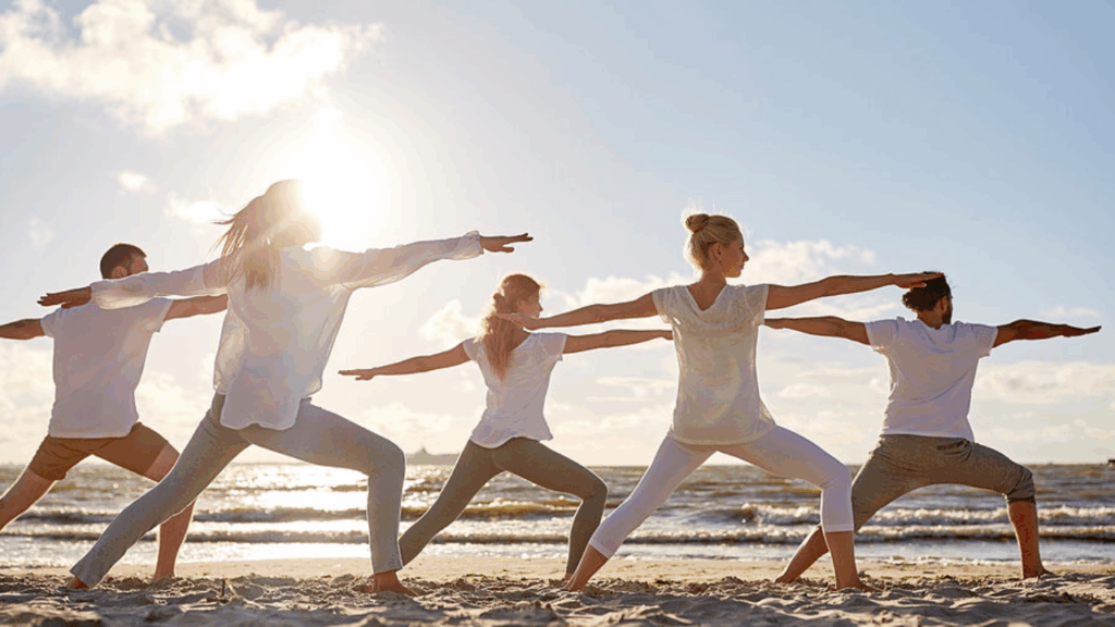 People practicing yoga on the beach during sunrise.