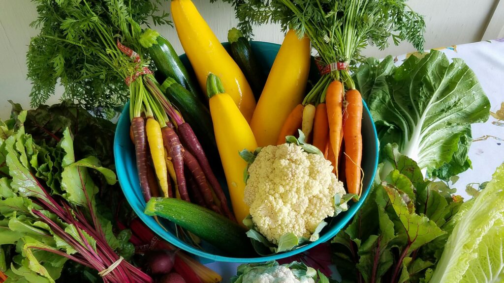 A bowl filled with colorful fresh vegetables including carrots, zucchini, and cauliflower.