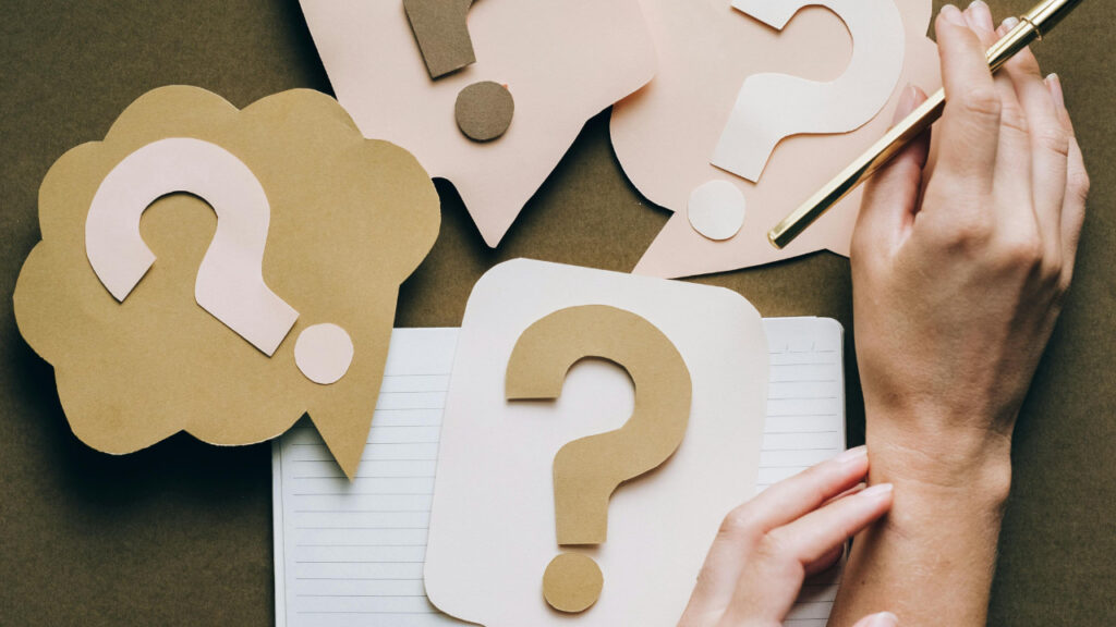 Cut-out question marks scattered over a notebook.