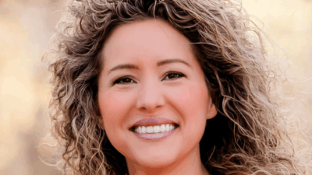 Smiling woman with curly hair and bright eyes.